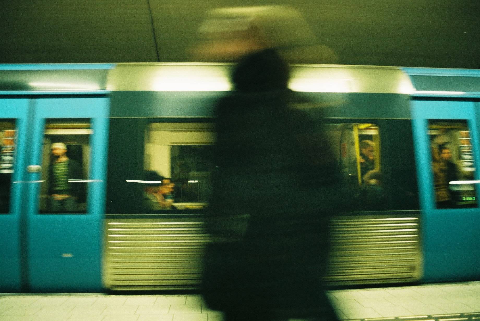 silhouette of a man in front of the blue subway train speeding up