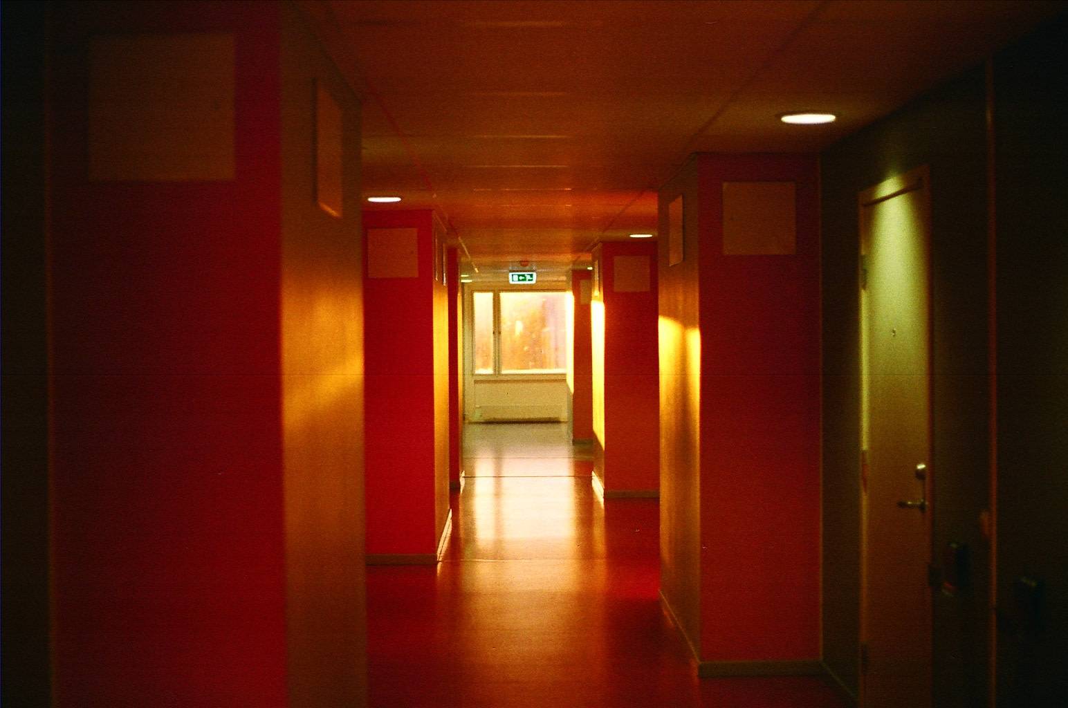 corridor lit up red with the sunlight shining through the window at the very end