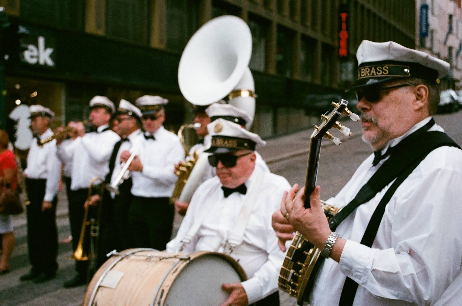 band members dressed in white and black uniforms performing music on the street