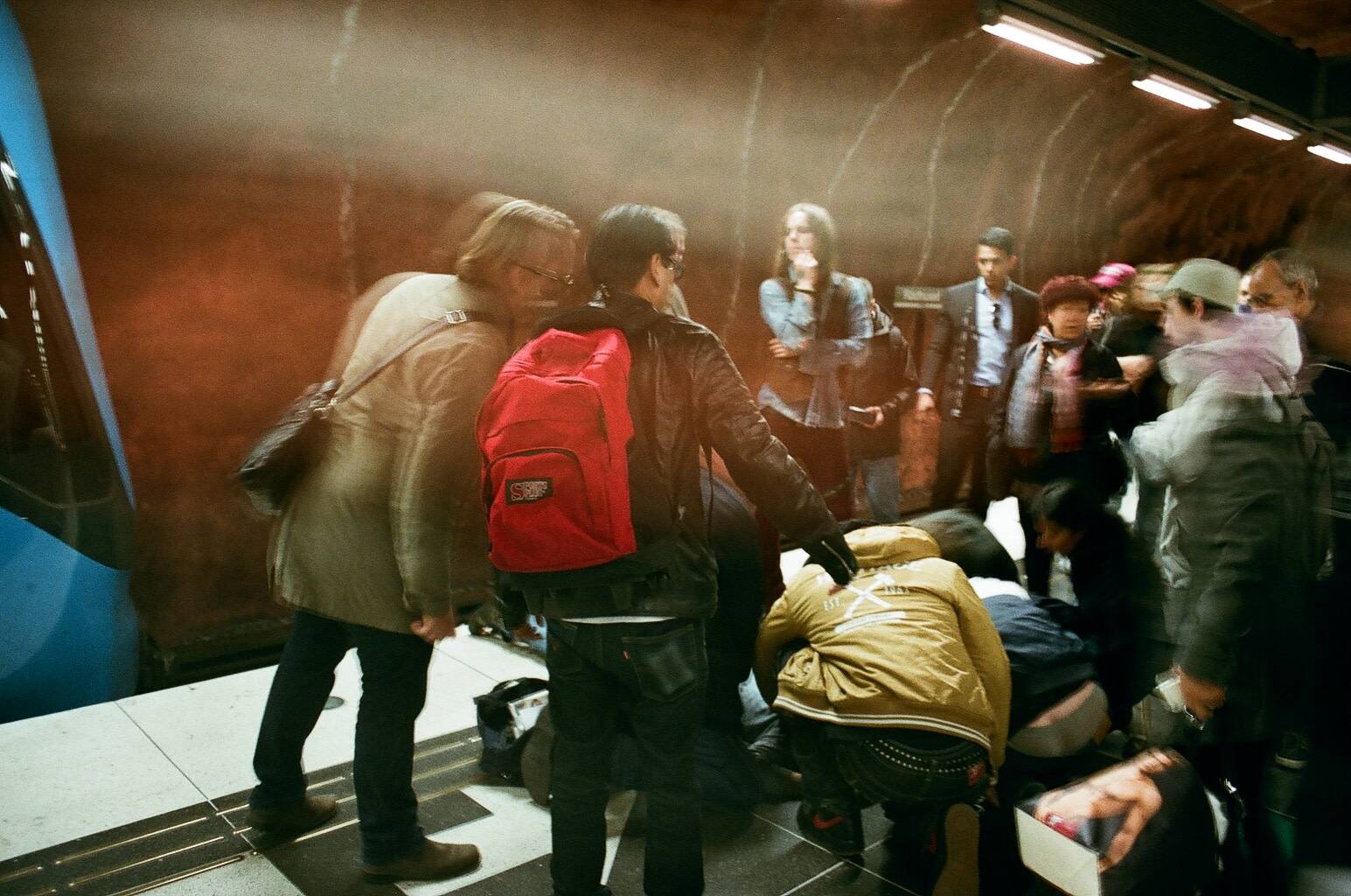 blurry figures of anxious people surrounding the injured man in the subway accident