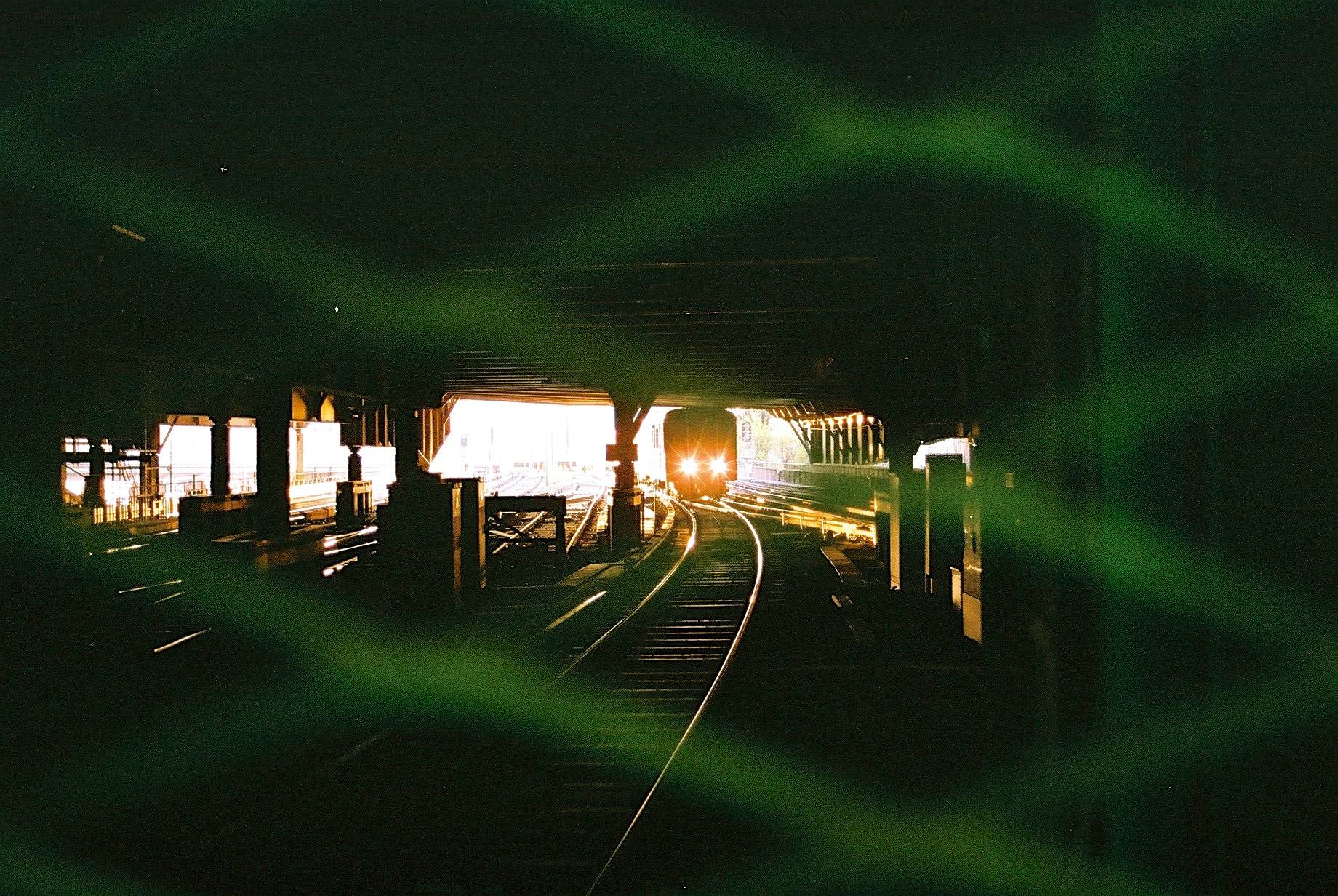 train headlights seen through the woven metal fence at end of the dark tunnel