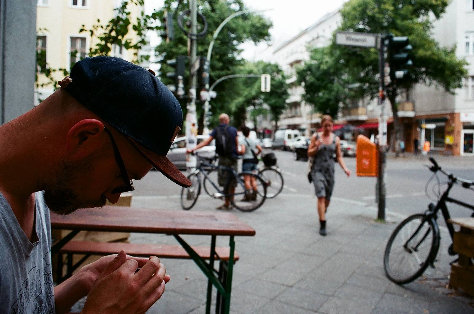 a man sitting by the benches on the sidewalk of a busy street, looking at his phone